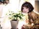 A woman sitting at a table next to a potted plant.