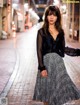 A woman in a black shirt and a black and white skirt.