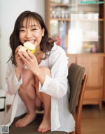 A woman sitting on a chair eating an apple.