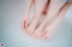 A woman's feet in a bathtub with water on them.