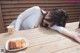 A woman laying on a wooden table next to a plate of food.