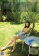 A woman sitting on a white chair in a garden.