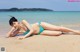 A woman in a blue bikini laying on the beach.