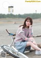 A woman sitting on a beach next to a bike.